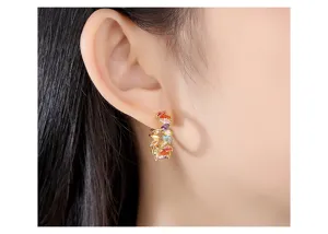 Macro detail shot of elegant colored zircon C-shaped hoop earrings worn on an earlobe