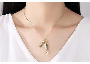 Macro view of a creative gold candy and pill pendant necklace on a female model neck.