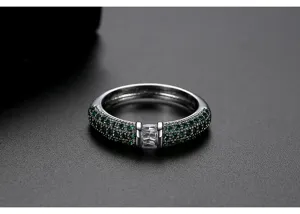 Vista detallada de anillo plateado con circonitas verdes y una piedra baguette transparente