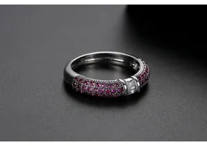Primer plano de un anillo con micropavé de circonitas rosas y piedra baguette clara.