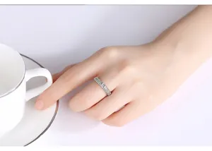 Primer plano de un anillo de plata con circonitas en un dedo tocando una taza.