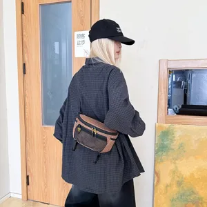 Λεπτομερής προβολή της καφέ καρό τεχνικής τσάντας μέσης που φοριέται χιαστί στο στήθος