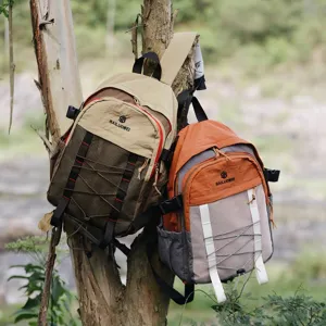 Dos mochilas de senderismo en estilos bicolor marrón y naranja colgadas de un árbol