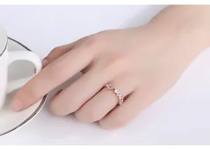 Vista de cerca de un elegante anillo de oro rosa con piedras de circonita en mano