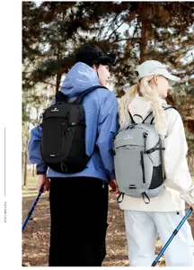 Pareja de excursionistas con mochilas ligeras en negro y gris en un sendero forestal.