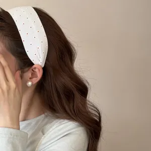 Dettaglio di un cerchietto in tessuto a fiori bianchi su una modella con capelli lunghi