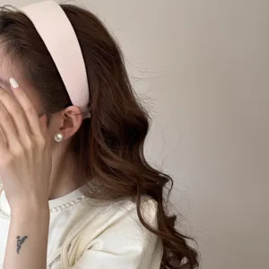 Detail of a wide pink sponge headband worn by a model with wavy brown hair.