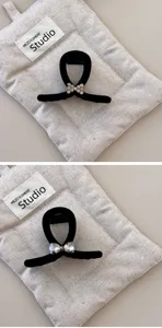 Macro view of two black velvet hair claw clips with elegant rhinestone bow details