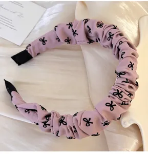 Detalle de diadema de tela fruncida rosa con elegantes lazos negros