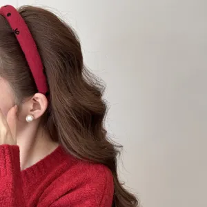 Detailed side view of a red padded headband featuring black heart prints on wavy hair