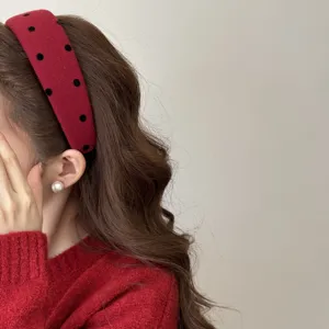 Vue latérale d'un serre-tête en velours rouge à pois noirs