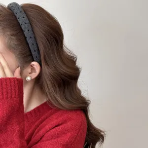 Close-up detail of a stylish grey wide headband with black heart pattern on a model