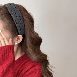 Détail d'un serre-tête en velours gris à pois porté sur des cheveux bruns ondulés