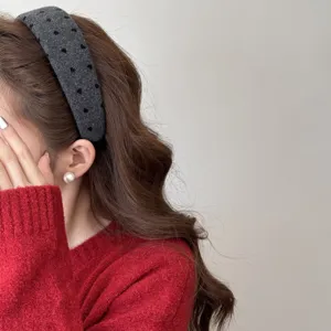 Gros plan d'un serre-tête en peluche gris à pois porté sur des cheveux bruns ondulés