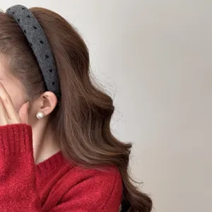 Detailed side view of a wide grey headband with heart patterns on wavy brown hair