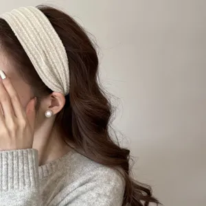 Gros plan d'un serre-tête en maille torsadée crème sur cheveux bouclés