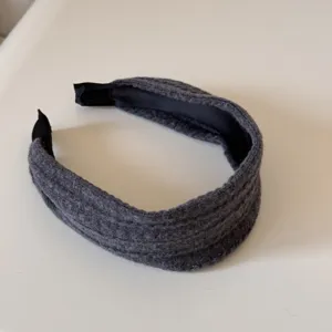 Détail montrant la texture tricotée grise et la doublure noire du serre-tête.