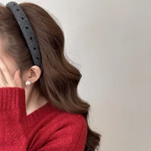 Detail view of a grey wide headband with heart patterns on an Asian model's hair.