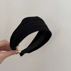 Gros plan d'un serre-tête en maille noire avec texture torsadée et doublure douce