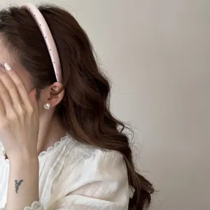 Vue de côté d'un élégant serre-tête rembourré rose à pois avec des boucles d'oreilles