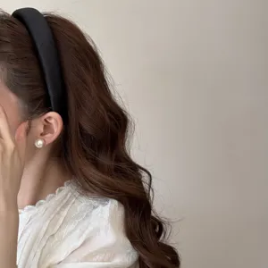 Gros plan d'un serre-tête noir à pois et d'une boucle d'oreille en perle sur modèle