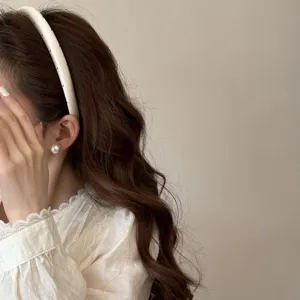 Gros plan élégant d'un serre-tête rembourré blanc à pois sur une femme aux cheveux bruns.