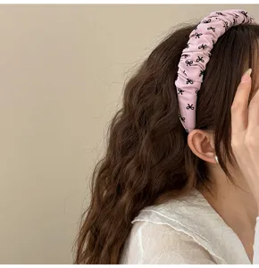 Primer plano de diadema de tela rosa rizada con lindos patrones de lazos negros