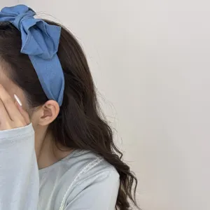 Close-up van een Franse retro denim haarband met een grote strik gedragen door een vrouw.