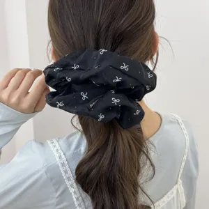 Vue détaillée d'un chouchou noir surdimensionné avec des motifs de nœuds blancs.