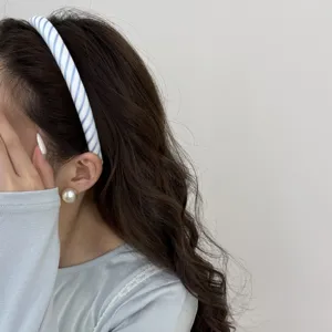 Close-up of a blue and white striped headband worn on wavy brown hair