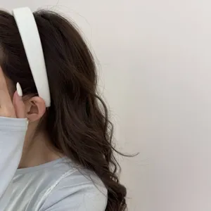 Détail d'un serre-tête minimaliste de couleur crème avec un motif discret de nœud.