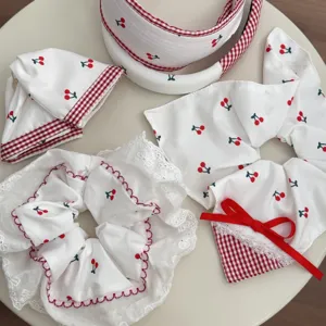Detailed view of sweet cherry print hair accessory set with white lace and red gingham