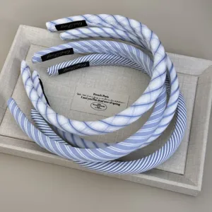 Close-up detail of stylish light blue and white striped fabric headbands on a linen display tray.