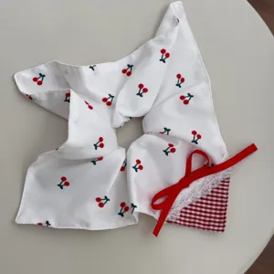 Detail view of a white lace scrunchie featuring red cherry patterns and a cute bow.
