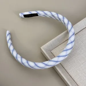 Detailed view of the blue and white striped fabric headband with its inner logo tag.