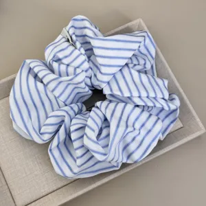 Detail view of a blue and white striped oversized fabric scrunchie in a gift tray