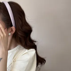 Detalle en primer plano de una diadema acolchada lavanda en el cabello ondulado