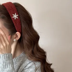 Close-up detail view of a festive burgundy plush headband with rhinestone snowflake