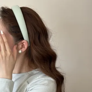 Vue détaillée d'un serre-tête en éponge vert menthe sur un modèle aux cheveux bouclés