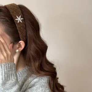Detail view of brown fuzzy headband featuring a sparkling rhinestone snowflake charm
