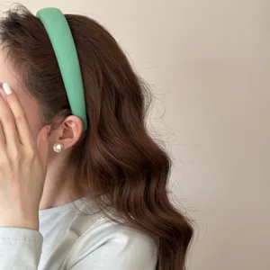 Gros plan d'un serre-tête rembourré vert menthe sur les cheveux ondulés d'un mannequin.