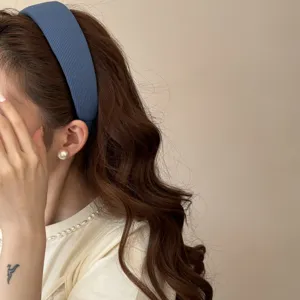 Detail shot of a wide blue sponge headband on a model with elegant wavy hair.