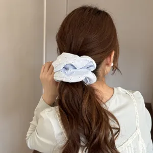 Vista dettagliata di un elastico per capelli in tessuto azzurro con motivi floreali.