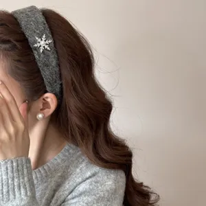 Detail shot of a grey plush headband with a sparkling rhinestone snowflake ornament