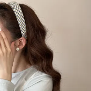 Vue détaillée d'un serre-tête à carreaux jaunes sur de longs cheveux bruns ondulés