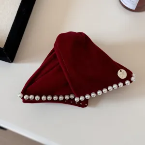 Close-up of retro red velvet headband with pearl trim and bow charm detail