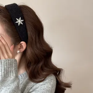 Detailed view of elegant plush black headband featuring a sparkling rhinestone snowflake