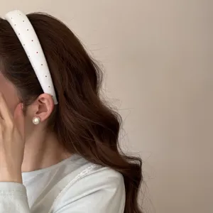 Primo piano di una fascia per capelli larga bianca a fiori e pois indossata da una modella