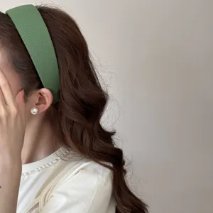 Close-up of a wide sage green sponge headband showing its soft fabric texture and elegant fit