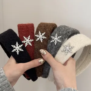 Macro view of five plush headbands with rhinestone snowflake ornaments in various colors.